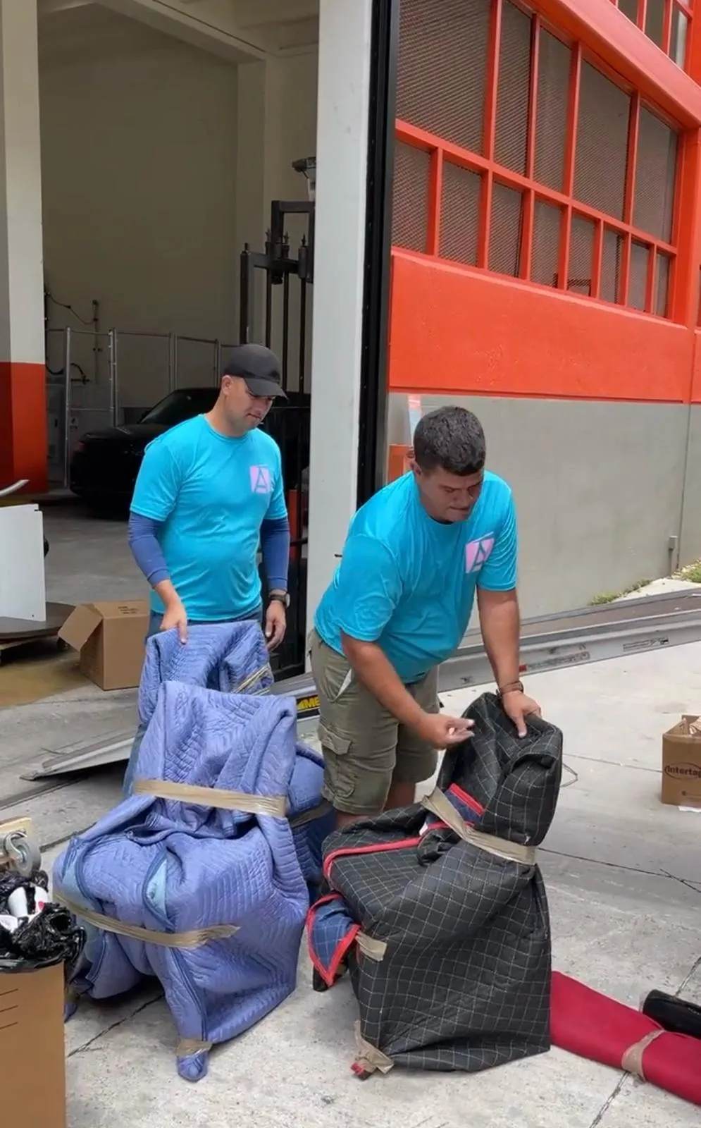 Allen & Son crew handling moving blankets and wrapped furniture at a job site
