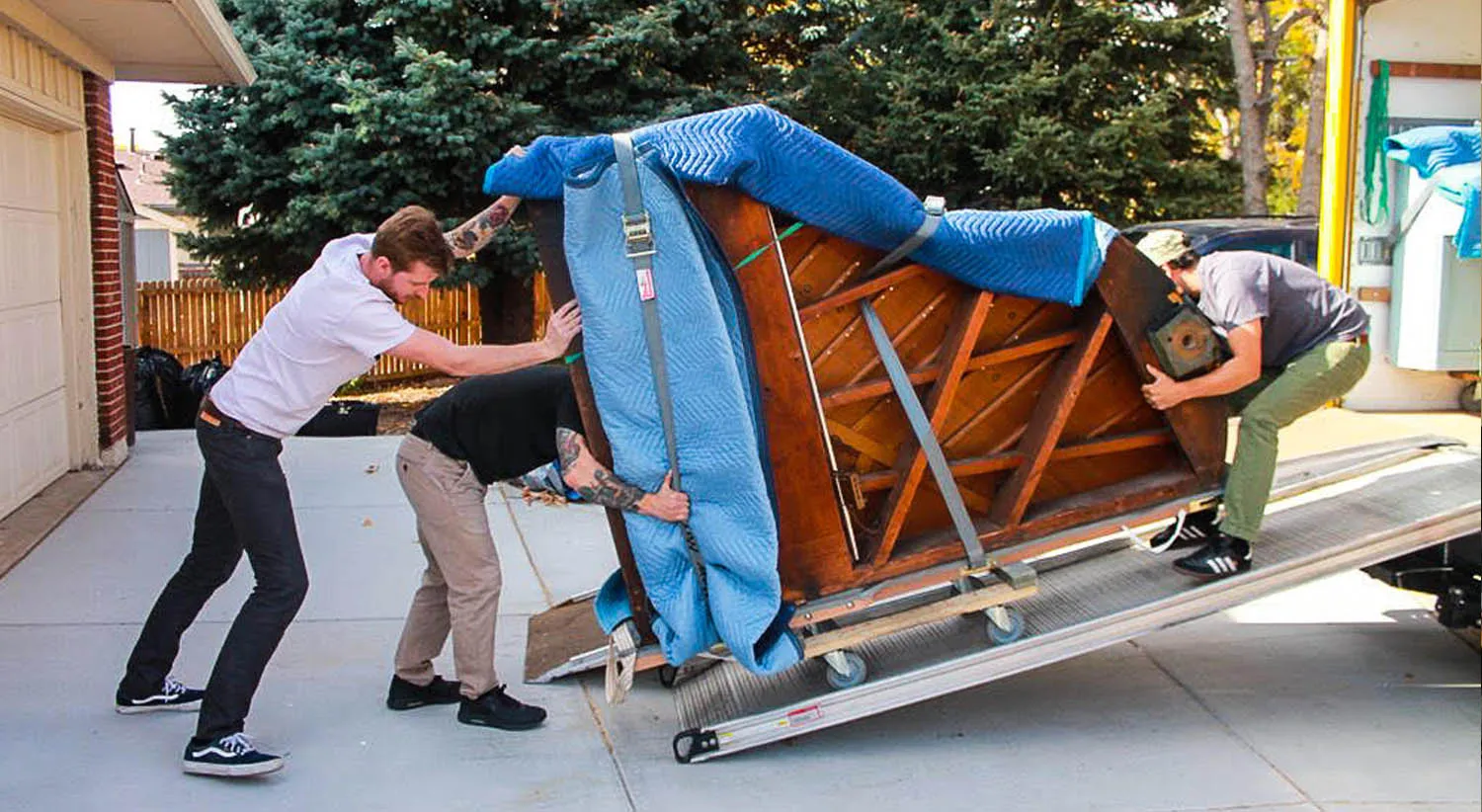 Movers sliding a wrapped piano down a ramp (stock photo)